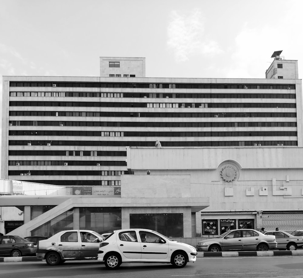 grayscale photo of parked vehicles outside building