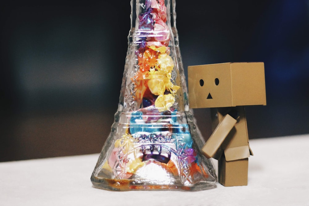 jouet de boîte humanoïde debout sur une bouteille en verre