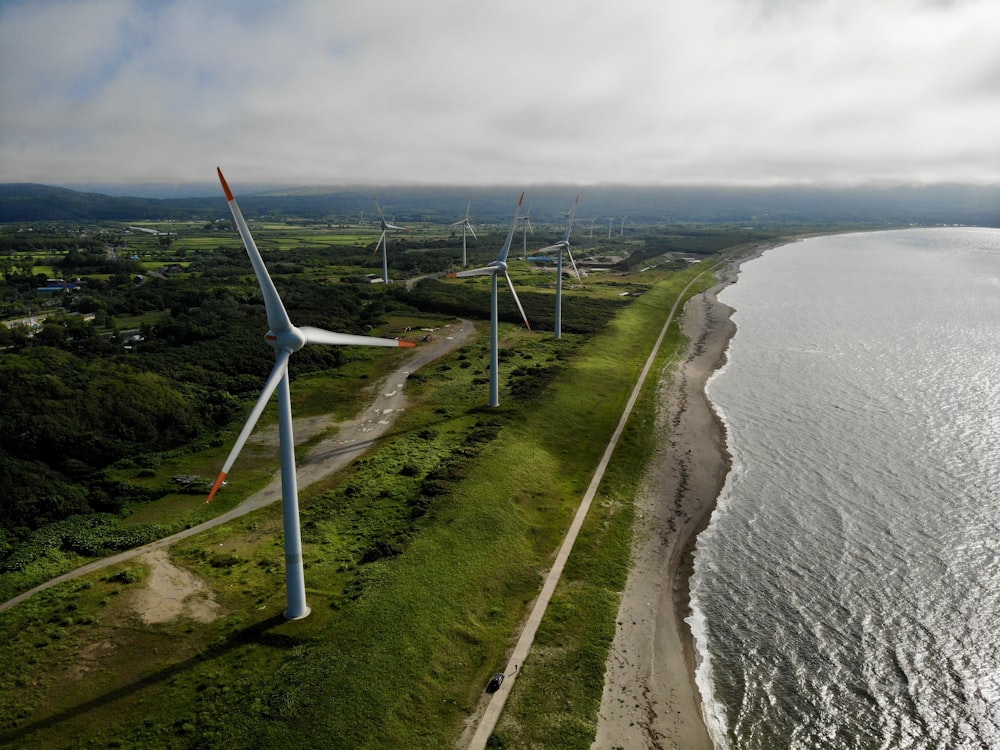 aerial photography of white windmills near body of water under white and blue sky