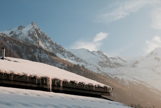 A freshly shingled roof blanketed lightly with snow against mountain backdrops.