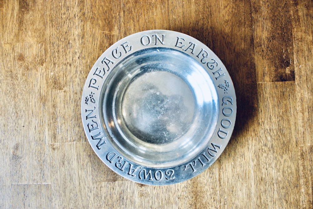 round grey stainless steel saucer on brown wooden surface