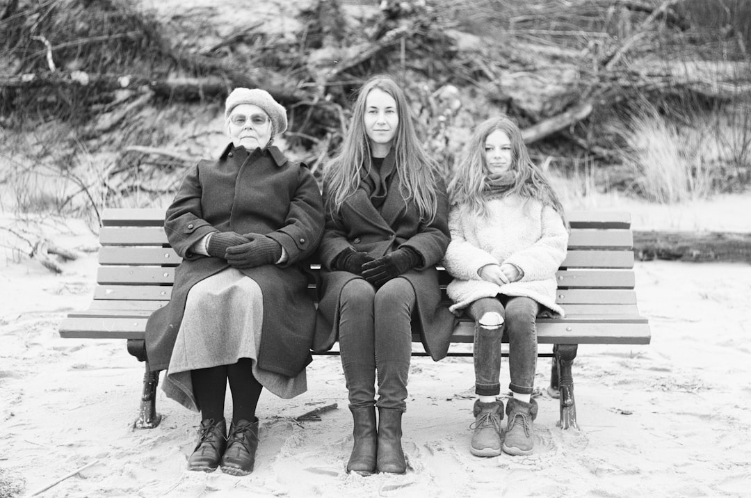 grayscale photo of three women sitting on bench