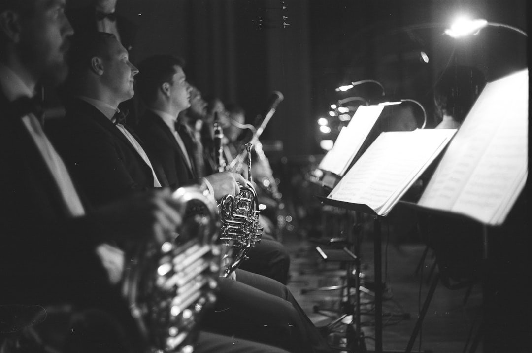 grayscale photo of musicians facing music stand