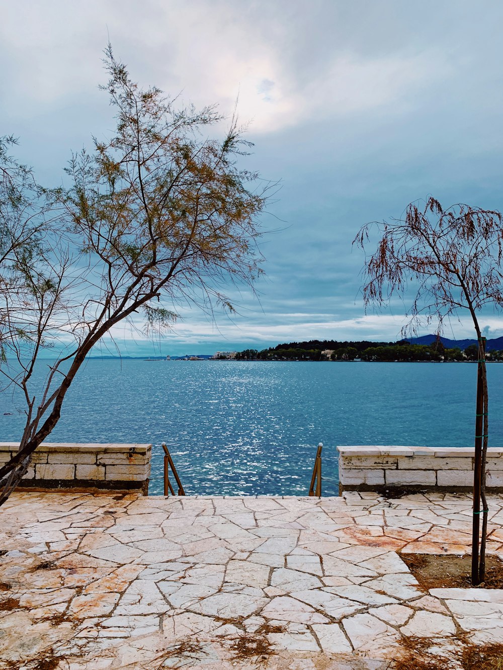 beige concrete hallway viewing blue body of water and mountain under white and blue sky