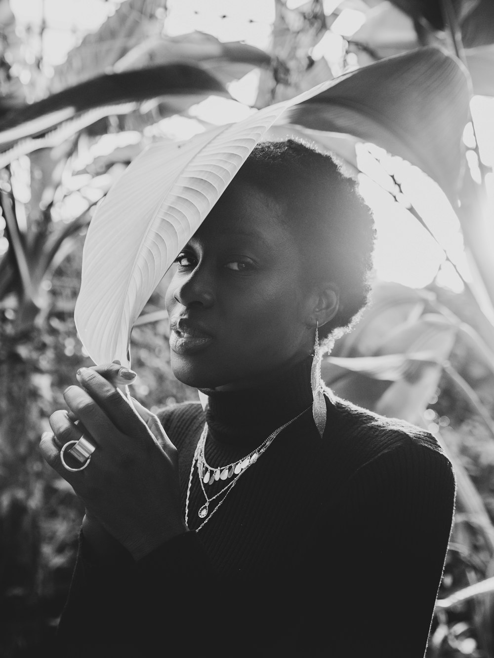 grayscale photography of woman hiding under plant