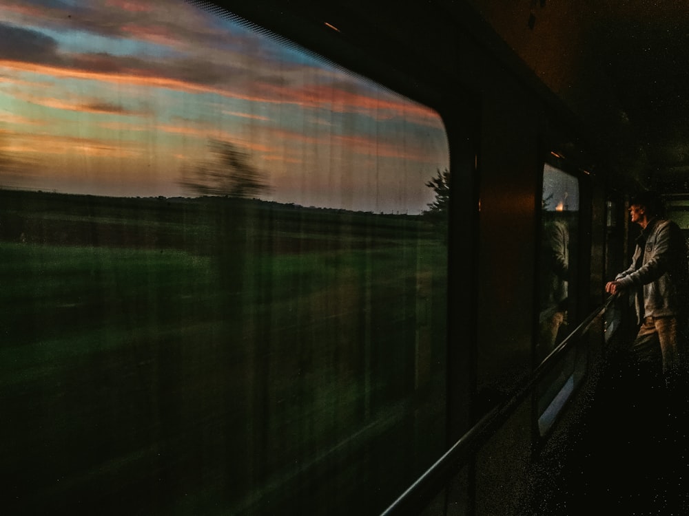 a man standing on a train looking out the window