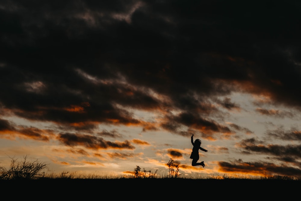 silhouette of jumping person during golden hour