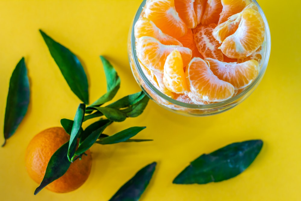 sliced orange fruits in clear glass bowl