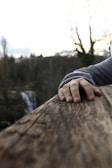A close-up of a weathered hand resting on a railing.