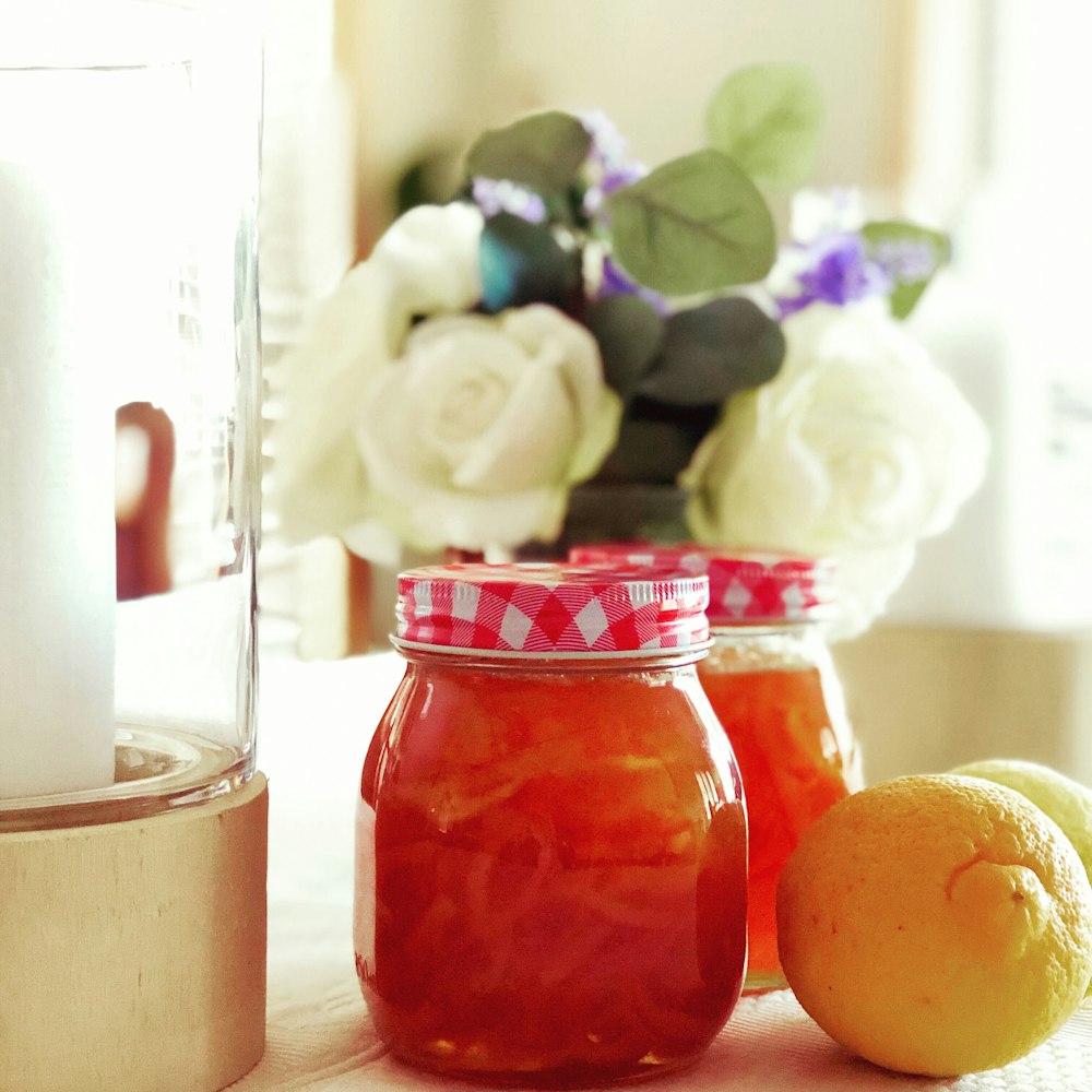 two glass jars near vase of flowers