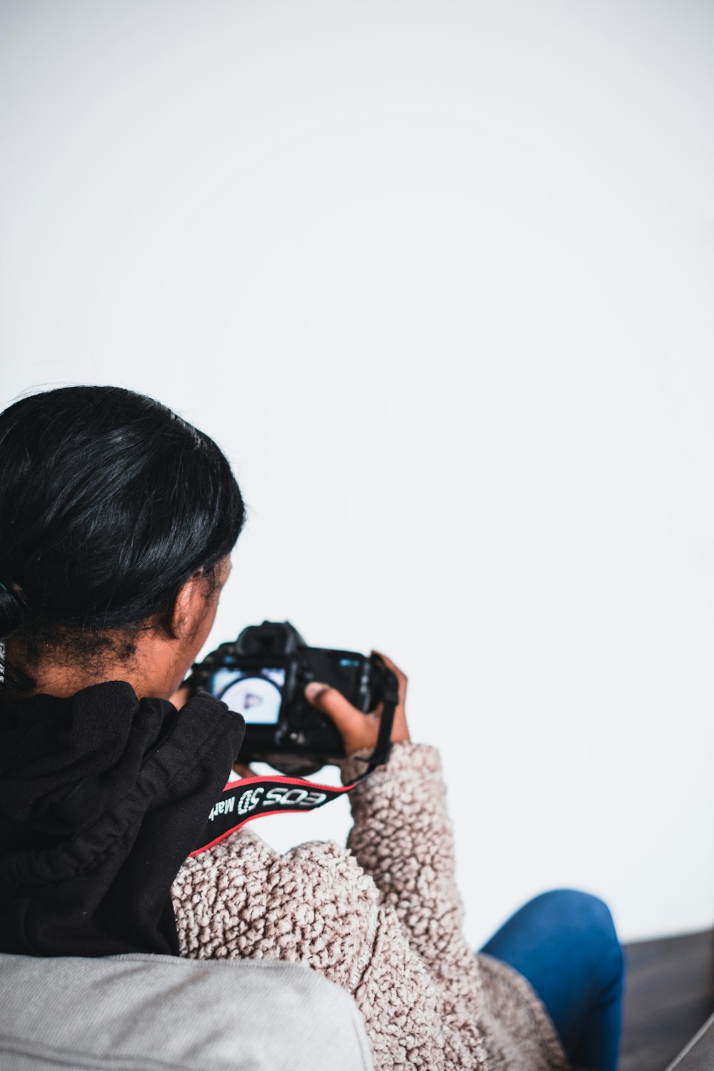 man sitting on sofa using DSLR camera