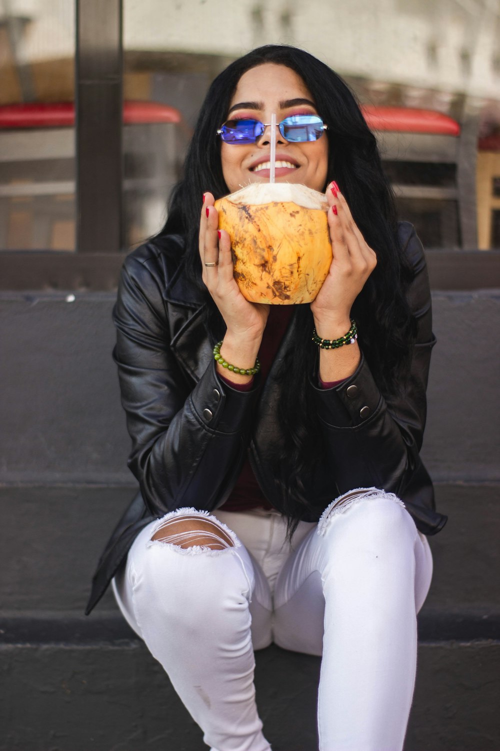 smiling woman sitting on stairs holding coconut fruit