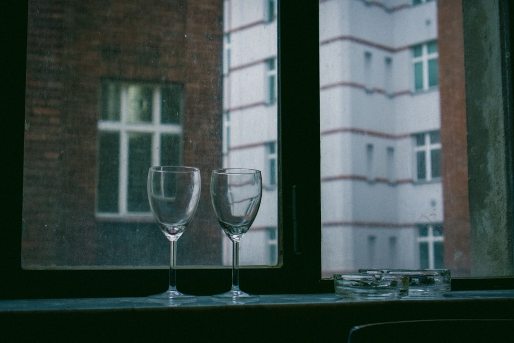 two wine glasses beside window