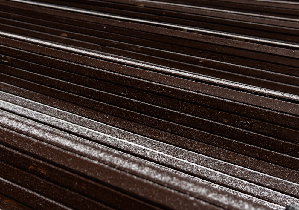a close up of a wooden bench with snow on it