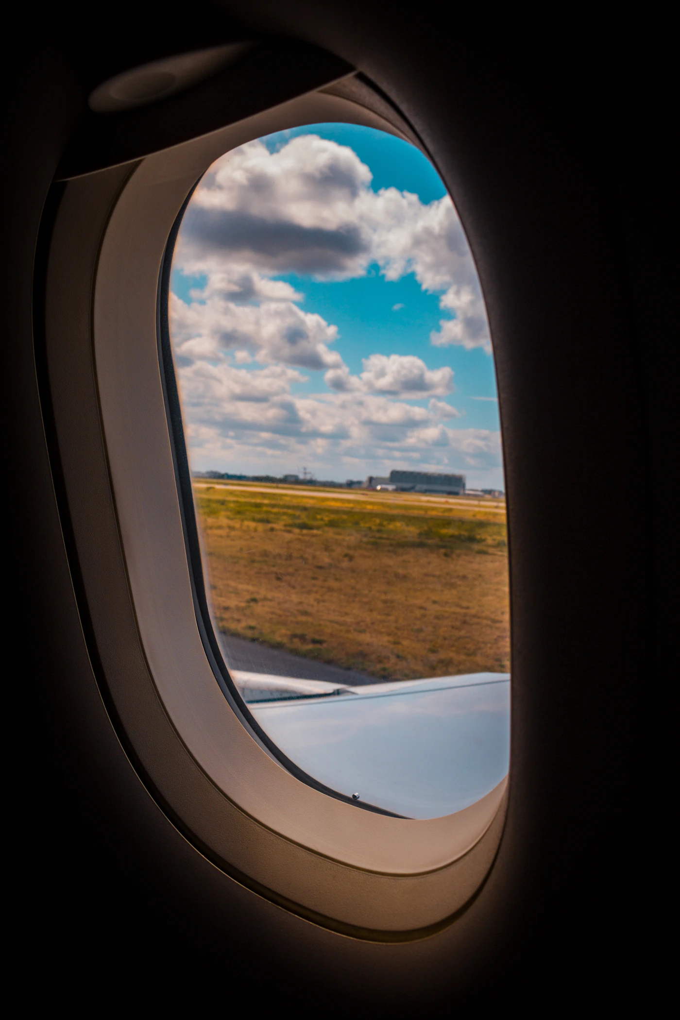 View through an airplane cabin window of the wing and sky on a Canadian flight