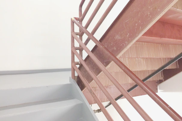 Straight metal staircase with black iron steps and a minimalist railing against a white wall