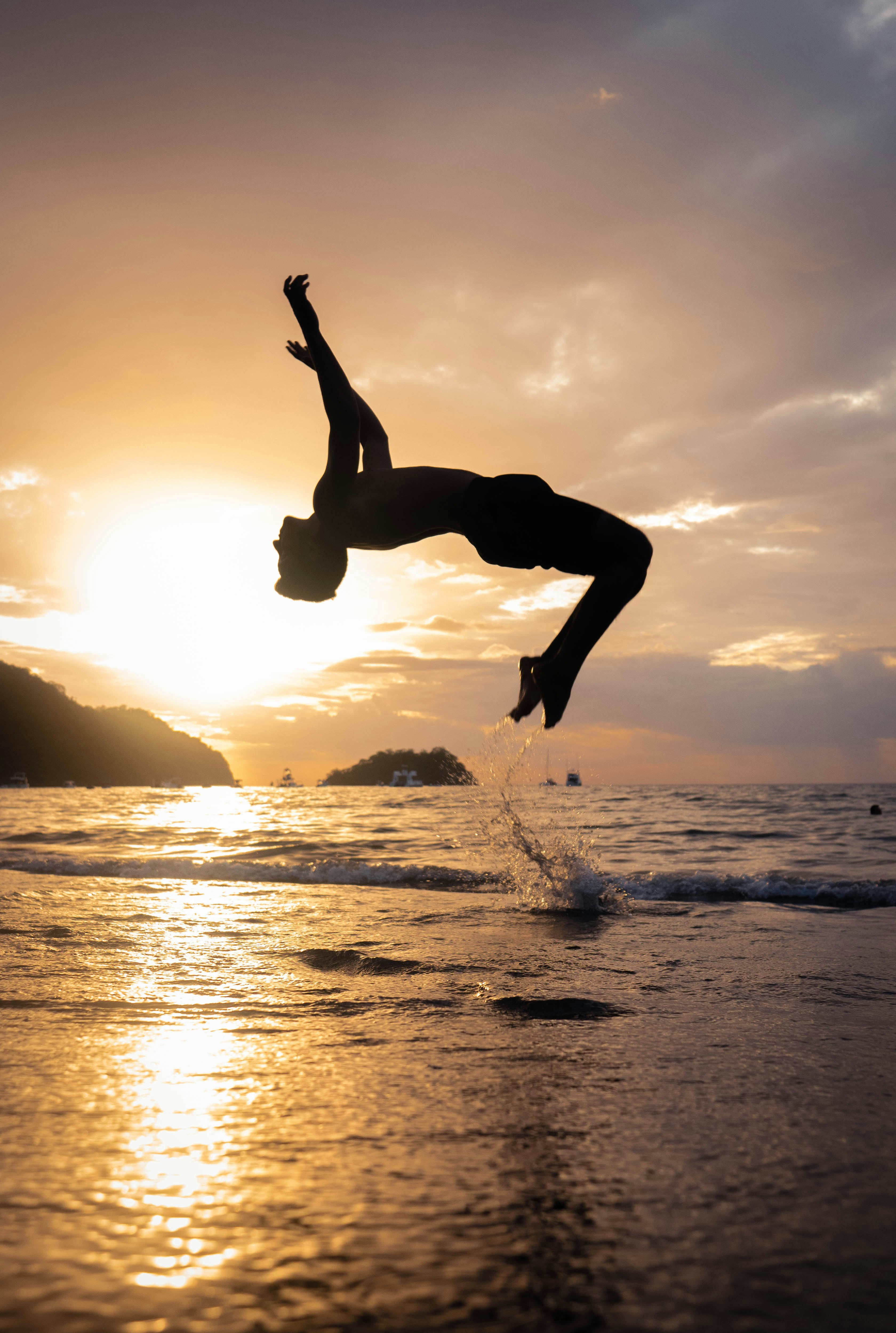 silhouette of man jumping on beach during sunset