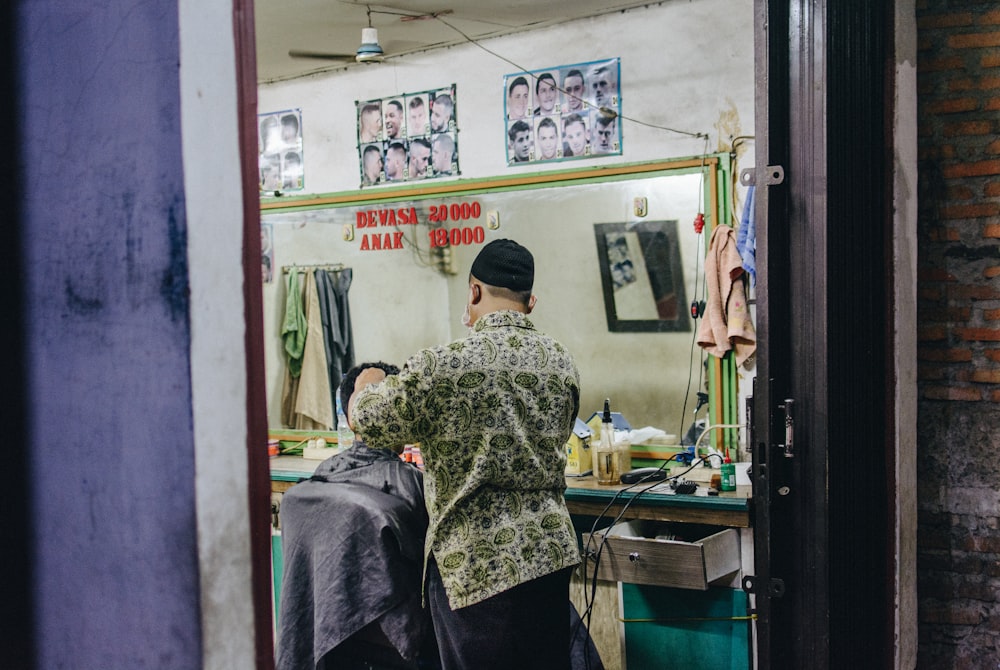 man standing while cutting hair of another person sitting