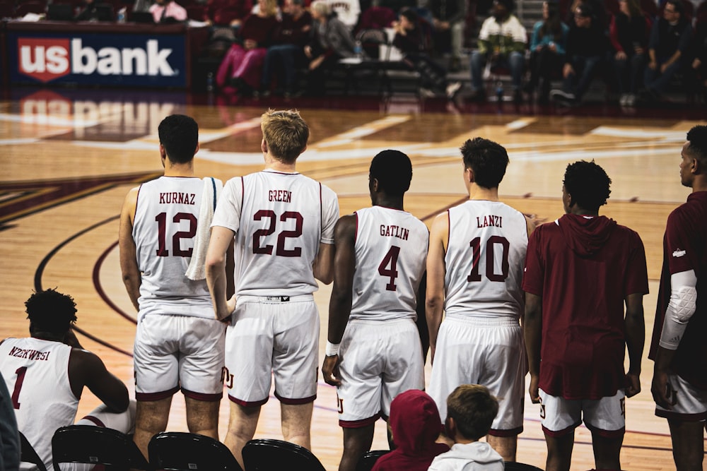 six basketball players standing and others are sitting in basketball court