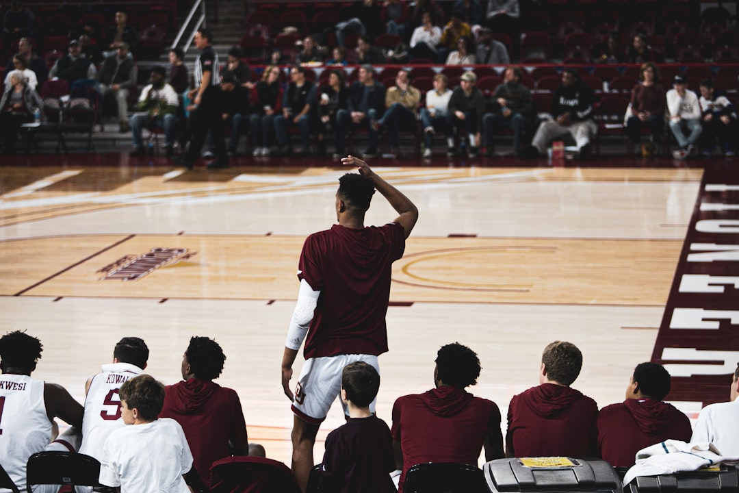 man standing while other players sitting near basketball court