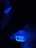A dark environment illuminated by bright blue neon light that highlights a sign with numbers and letters. The sign appears electronic or digital, possibly part of a public transportation system or an industrial setting.
