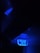A dark environment illuminated by bright blue neon light that highlights a sign with numbers and letters. The sign appears electronic or digital, possibly part of a public transportation system or an industrial setting.