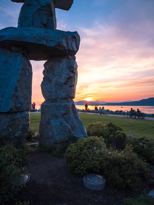 people on park viewing rock formations under orange sky in English Bay Beach Canada