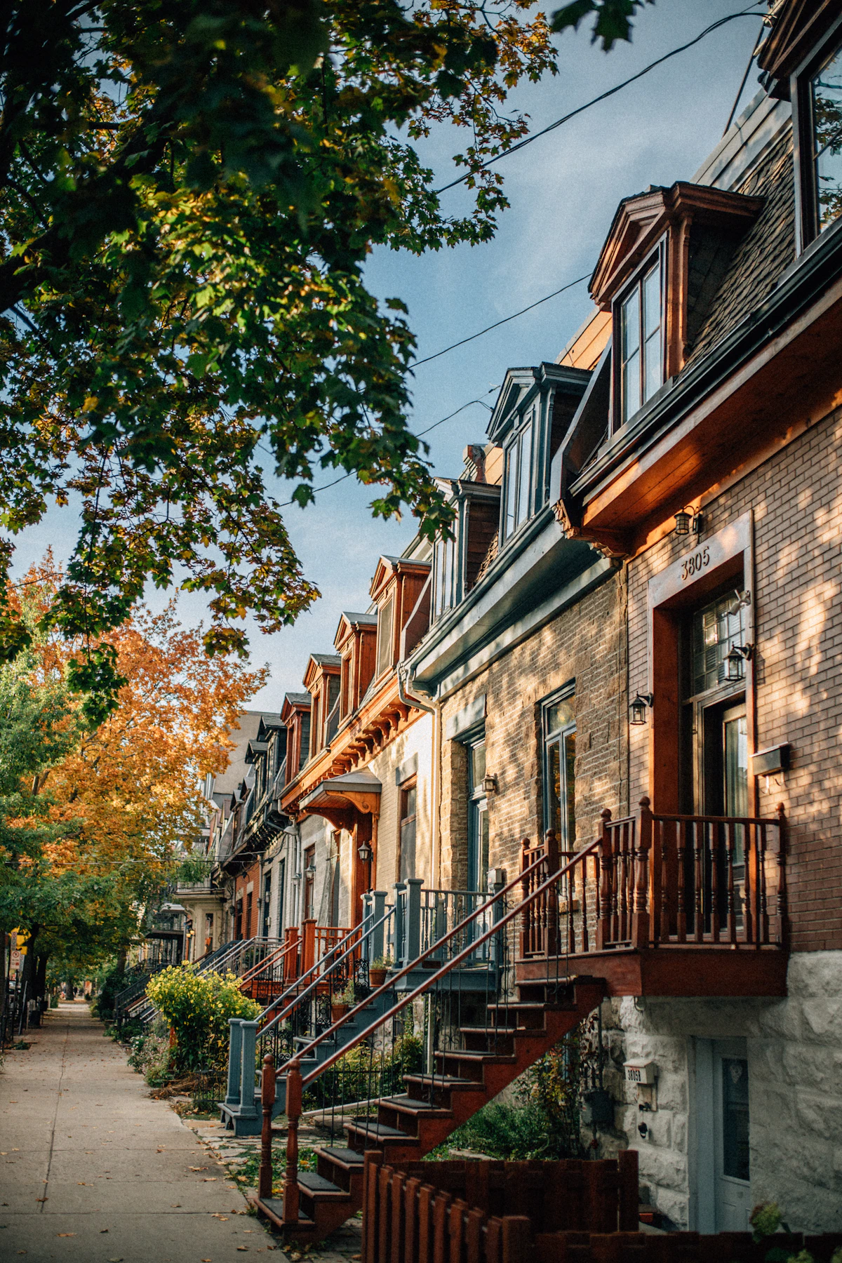 Colourful Montréal townhouses with exterior staircases beneath autumn trees