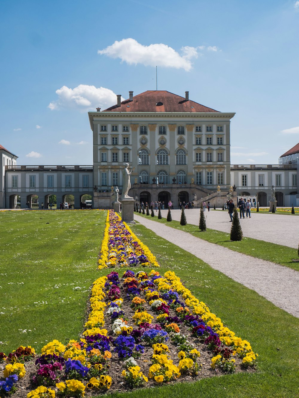 persone che camminano vicino al castello di Nymphenburg a Monaco di Baviera, Germania sotto cielo blu e bianco