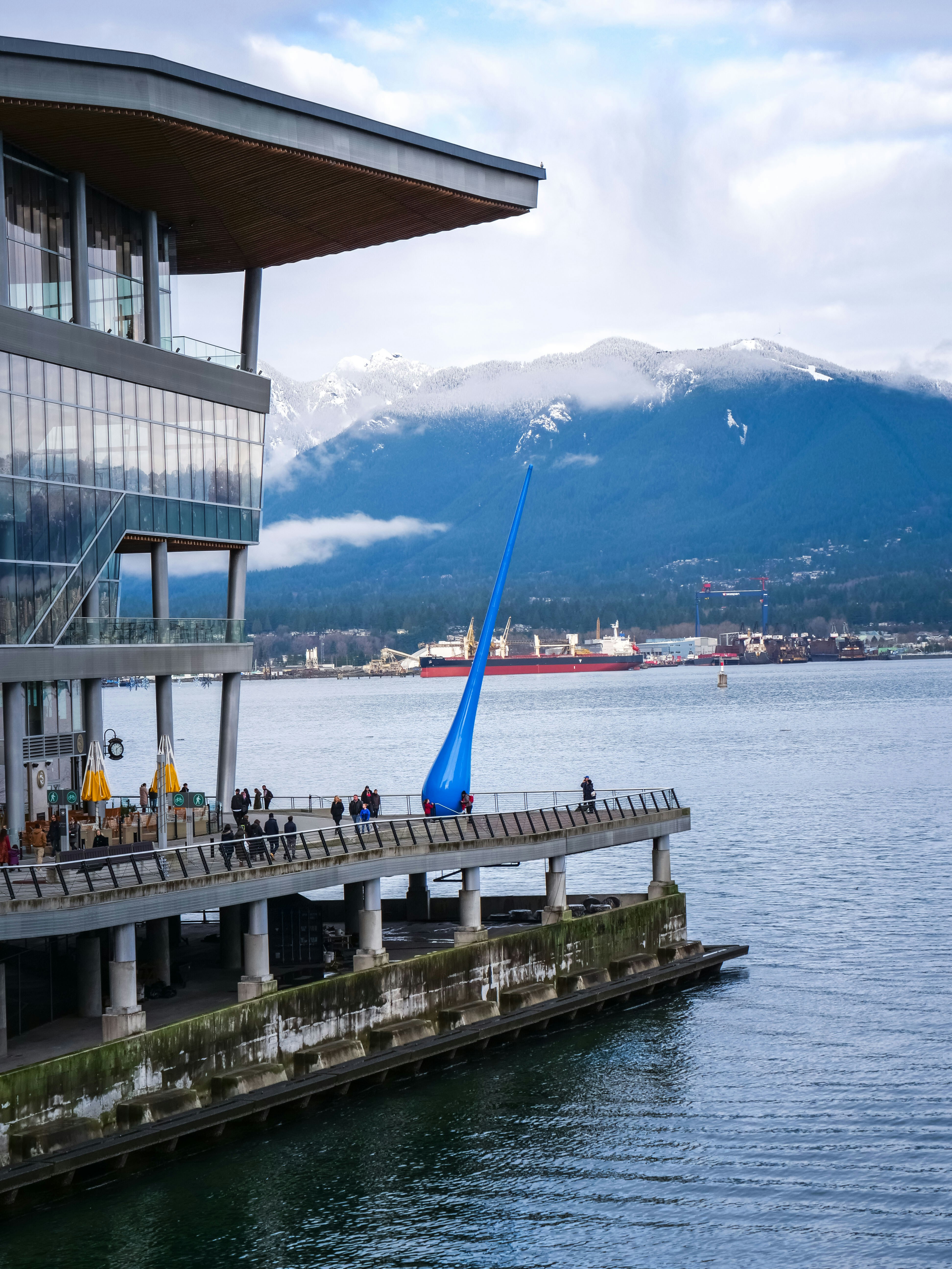 people in boat on body of water viewing mountain under white and blue sky