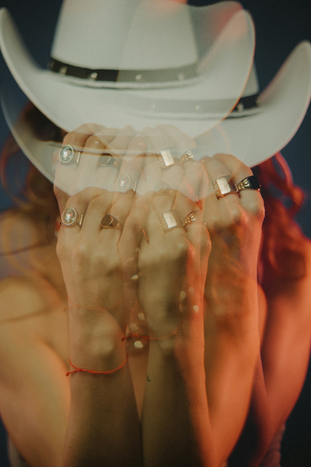 a woman wearing a cowboy hat covering her face with her hands