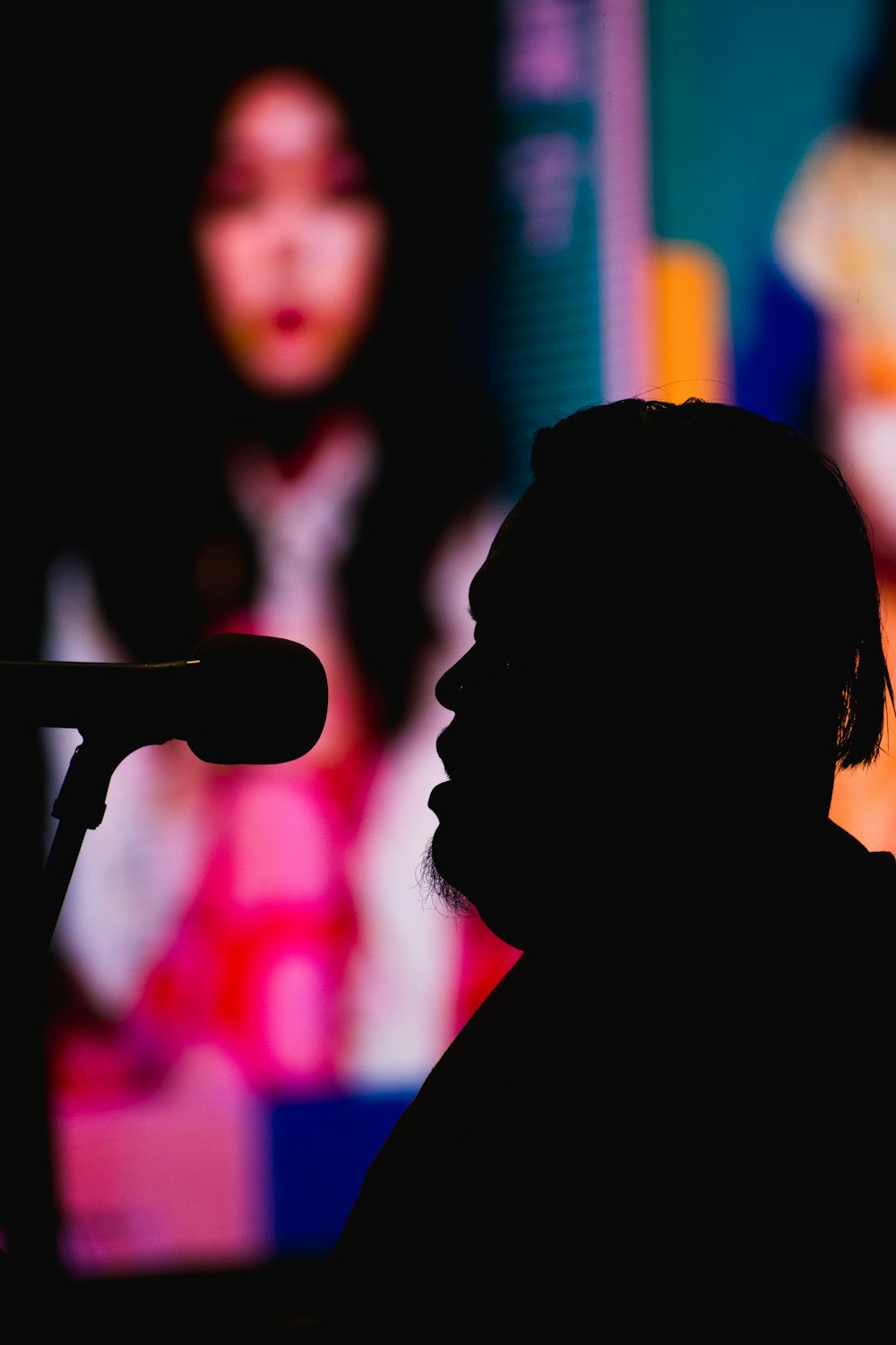 silhouette photography of man in front of a microphone