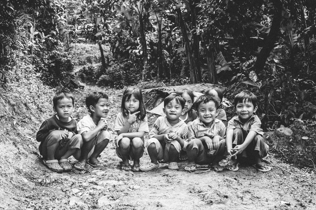 grayscale photography of six toddler surrounded by trees