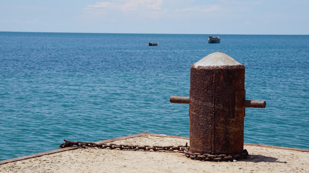 brown and gray metal mooring post near body of water