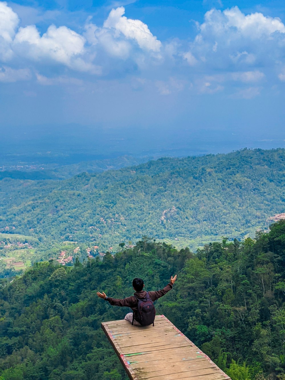 man sitting on dock on hill