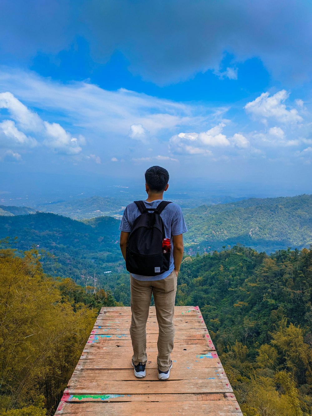 man carrying backpack while standing on wooden dock