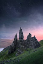 a group of rocks sitting on top of a lush green hillside