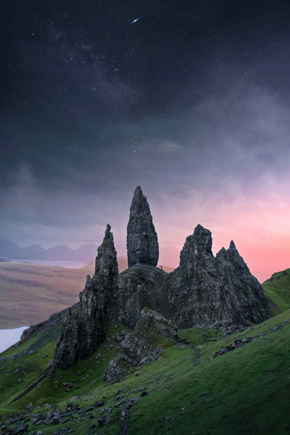 a group of rocks sitting on top of a lush green hillside