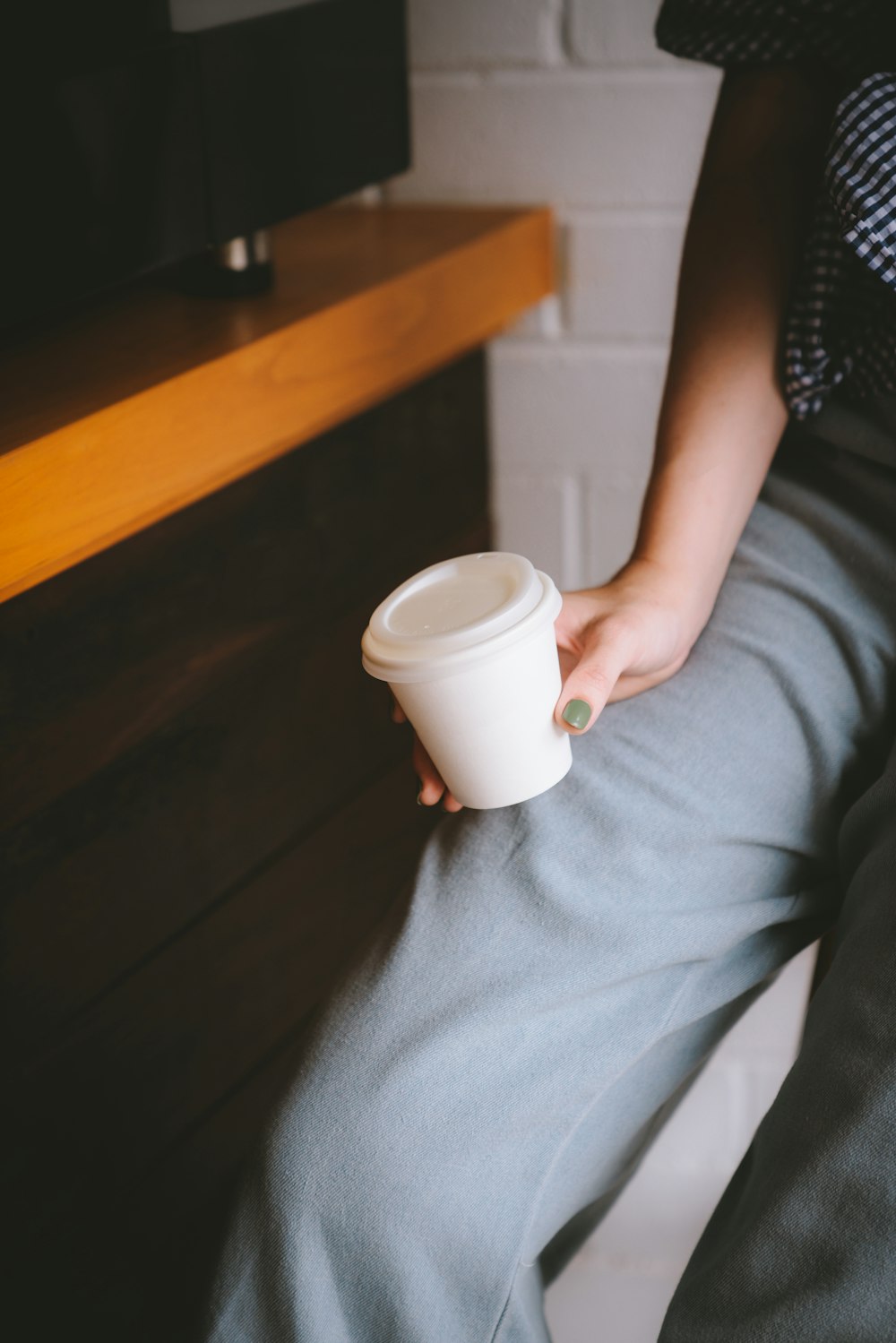 una persona seduta su una panchina che tiene una tazza di caffè