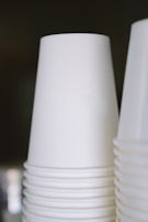 A stack of white disposable cups is arranged neatly, with a focus on their smooth and clean surface.