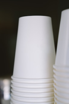 A stack of white disposable cups is arranged neatly, with a focus on their smooth and clean surface.