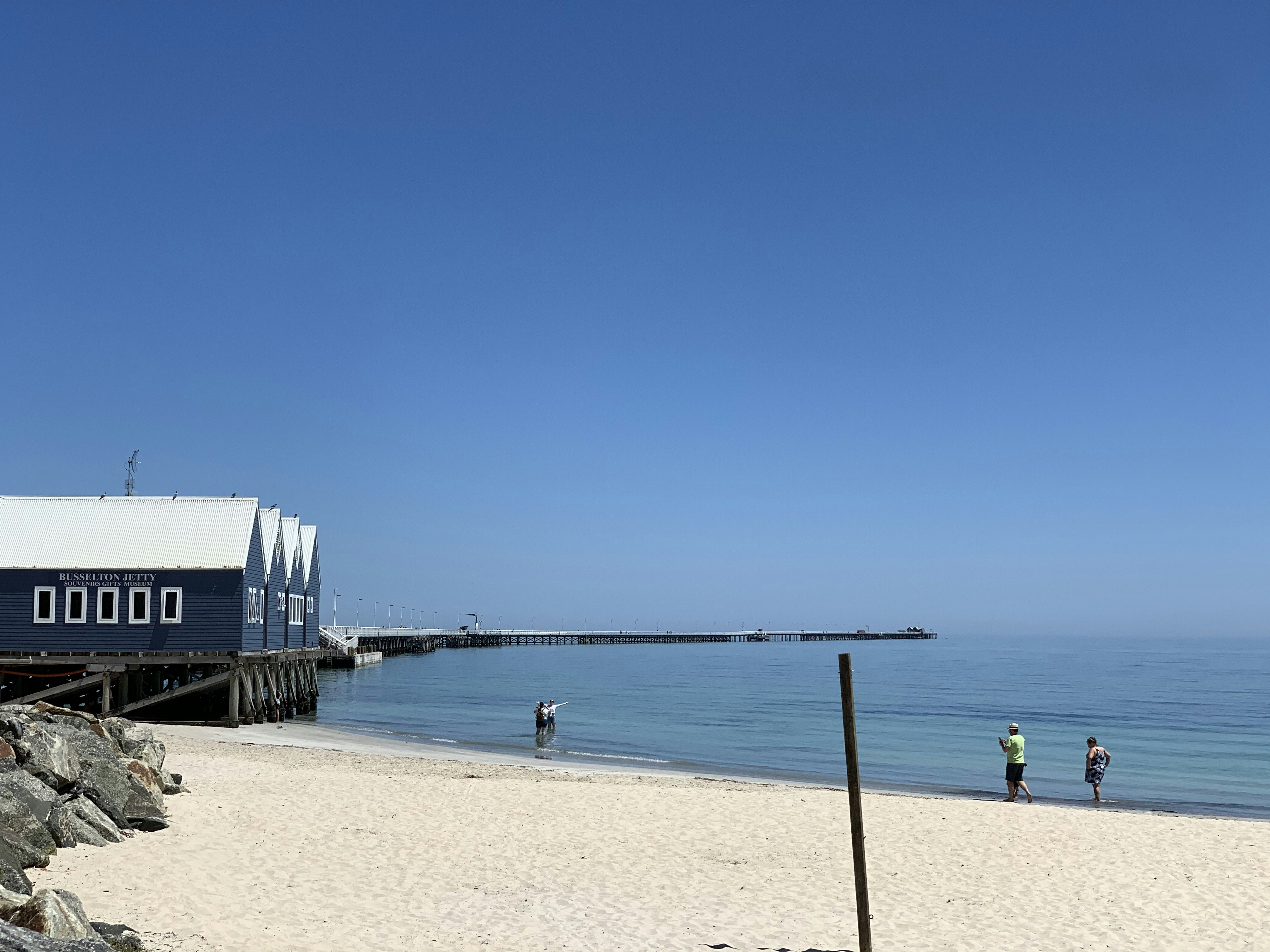 two person walking towards houses beside beach
