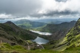 lake beside mountain under cloudy sky