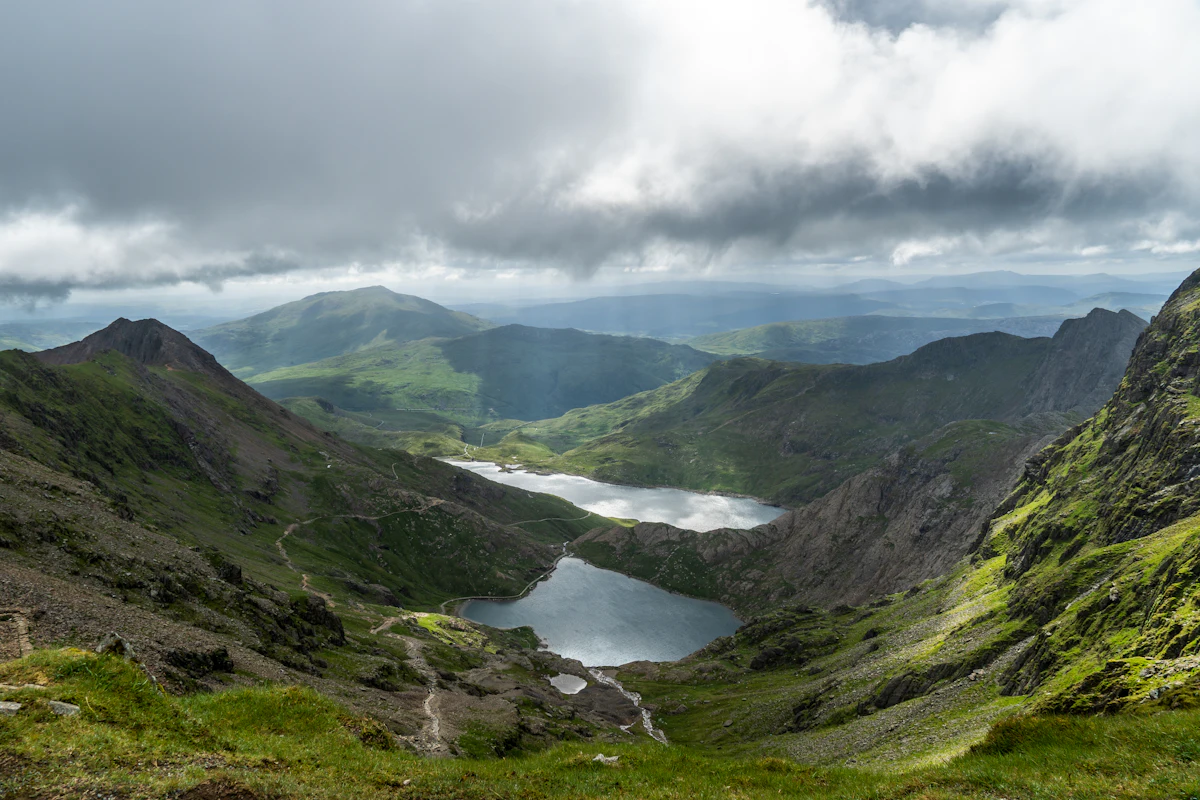 Two lakes in a green cwm far below, seen from high on Yr Wyddfa under heavy cloud