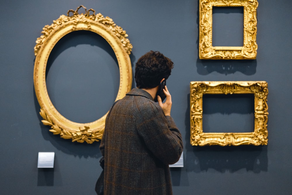 man in black jacket standing in front of brown wooden frames