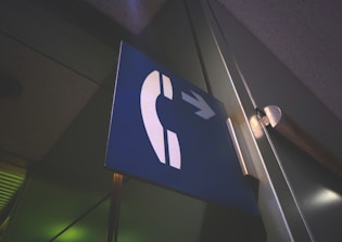 Close-up of a phone handset with a glowing call center sign in the background.