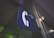 A close-up view of a blue sign with a white telephone symbol and an arrow pointing to the right. The sign is mounted on a green wall, with dim lighting contributing to a vintage or retro atmosphere.