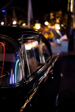 A classic vintage car shining under bright city lights