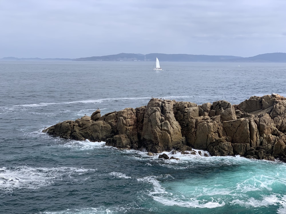 Barca bianca che naviga al mare vicino all'isola rocciosa marrone delle montagne