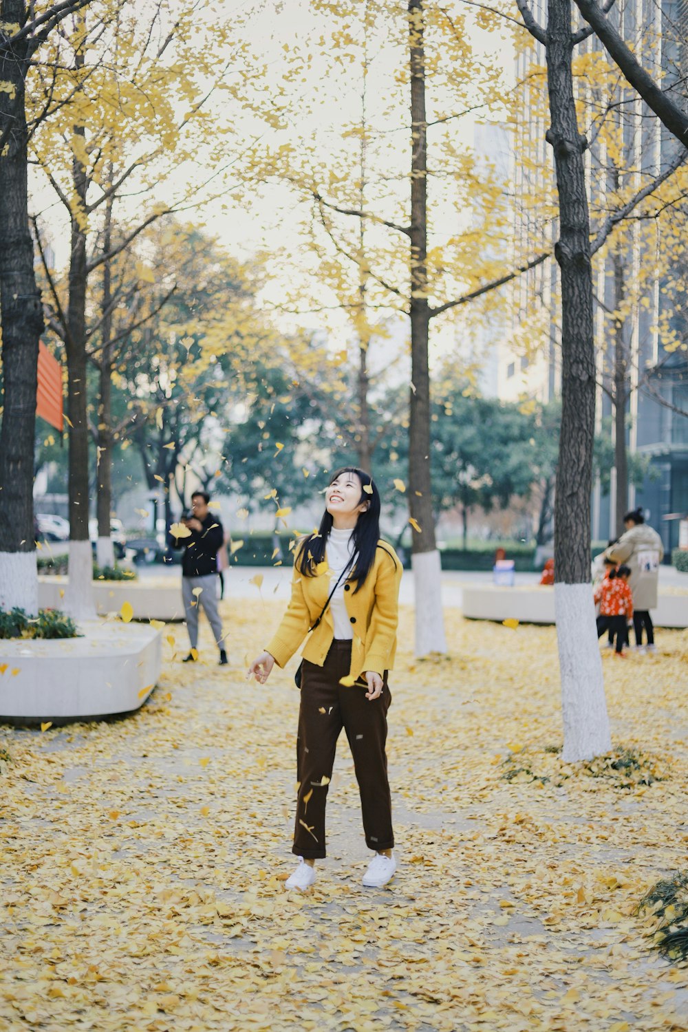 woman near trees with falling leaves